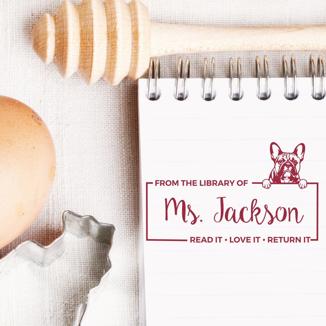 Custom library rubber stamp for Mrs. Jackson with dog icon and Read It, Love It, Return It on a notebook page.