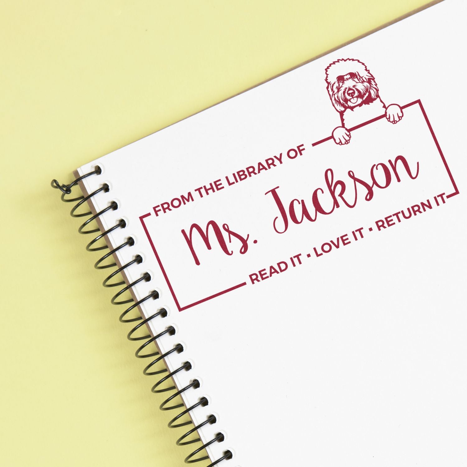 Custom library rubber stamp for Ms. Jackson reading Read It Love It Return It with dog illustration on notebook cover