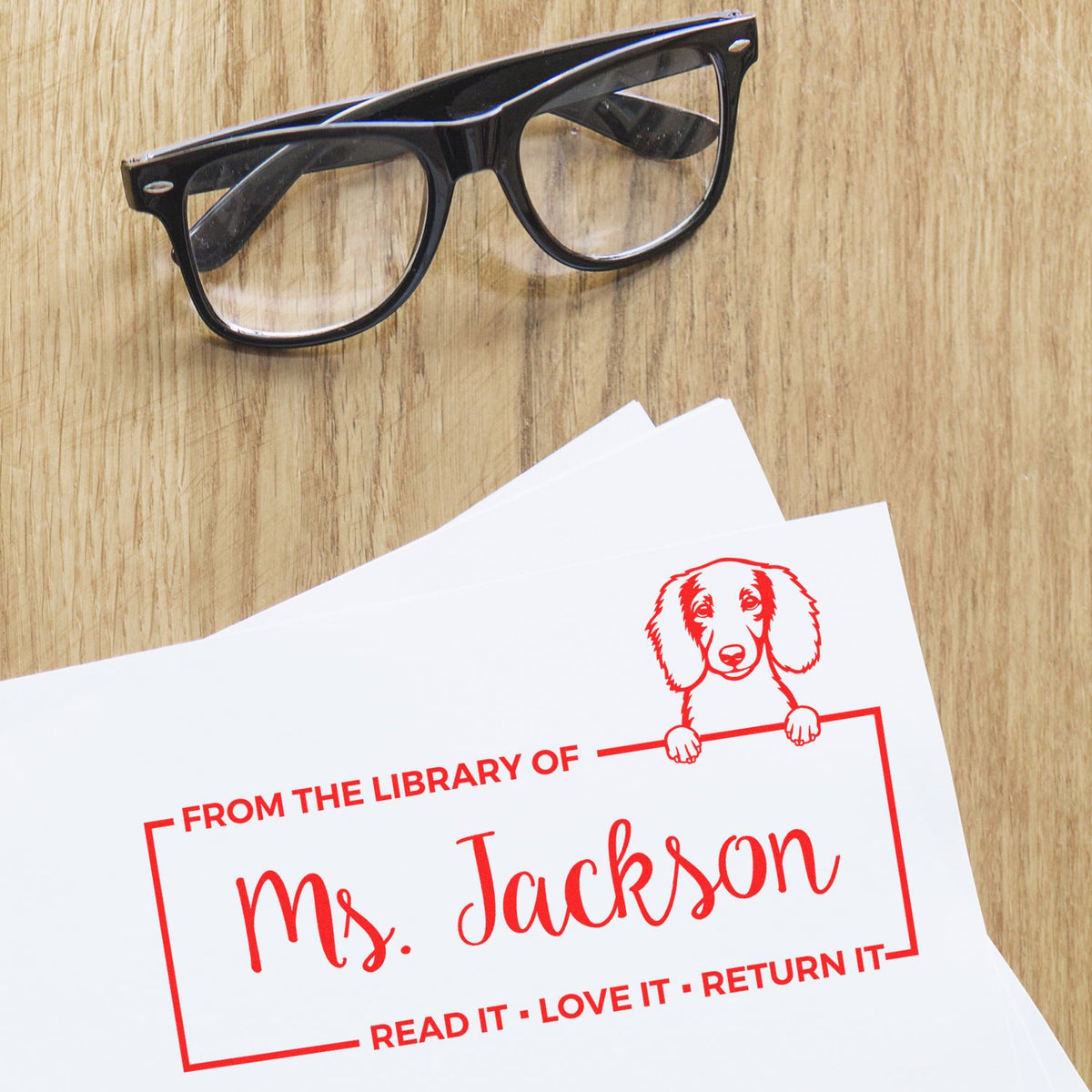 Custom rubber stamp on paper, featuring a personalized From the Library of Ms. Jackson bookplate with dog illustration.