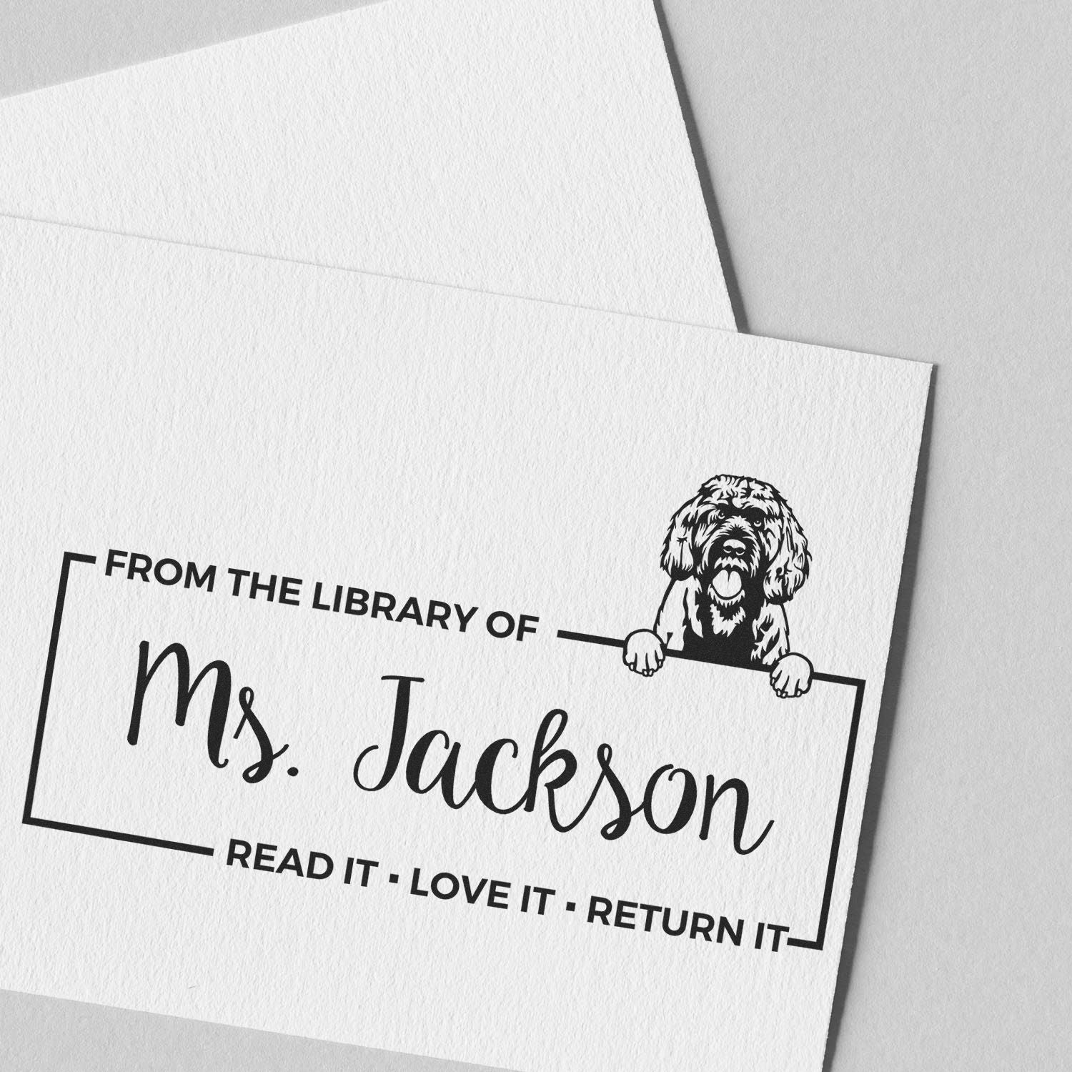 Personalized library book rubber stamp with dog illustration and From the Library of Ms. Jackson read-it-love-it-return-it text.