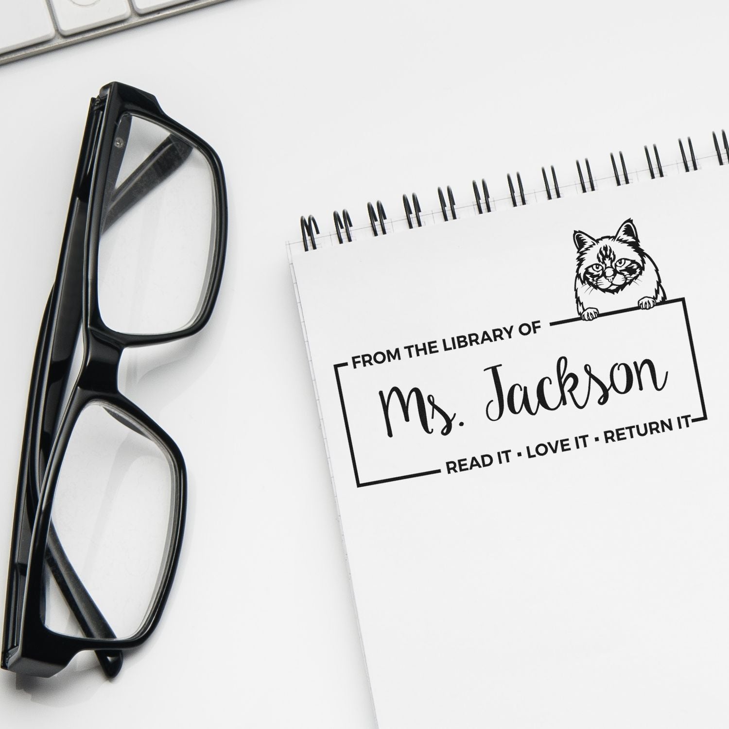 Personalized library rubber stamp impression with cat design for Ms. Jacksons book return labels and ownership marking.
