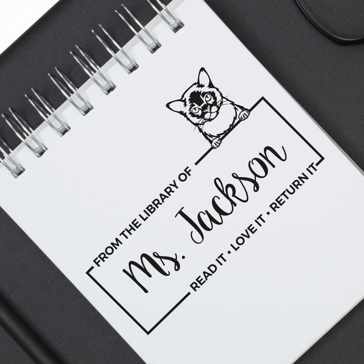 Custom library rubber stamp design with cat illustration and From the Library of Ms. Jackson return book label.