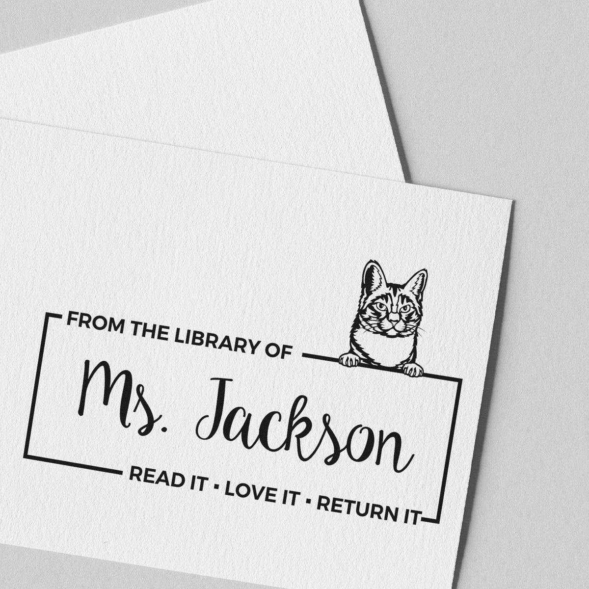 Personalized library rubber stamp with cat illustration for Ms. Jackson, featuring Read It, Love It, Return It bookplate.