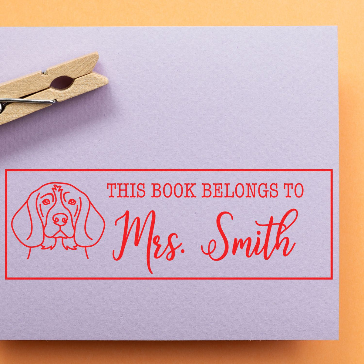 Custom rubber book stamp with dog illustration and This Book Belongs To Mrs. Smith personalized ex libris text.