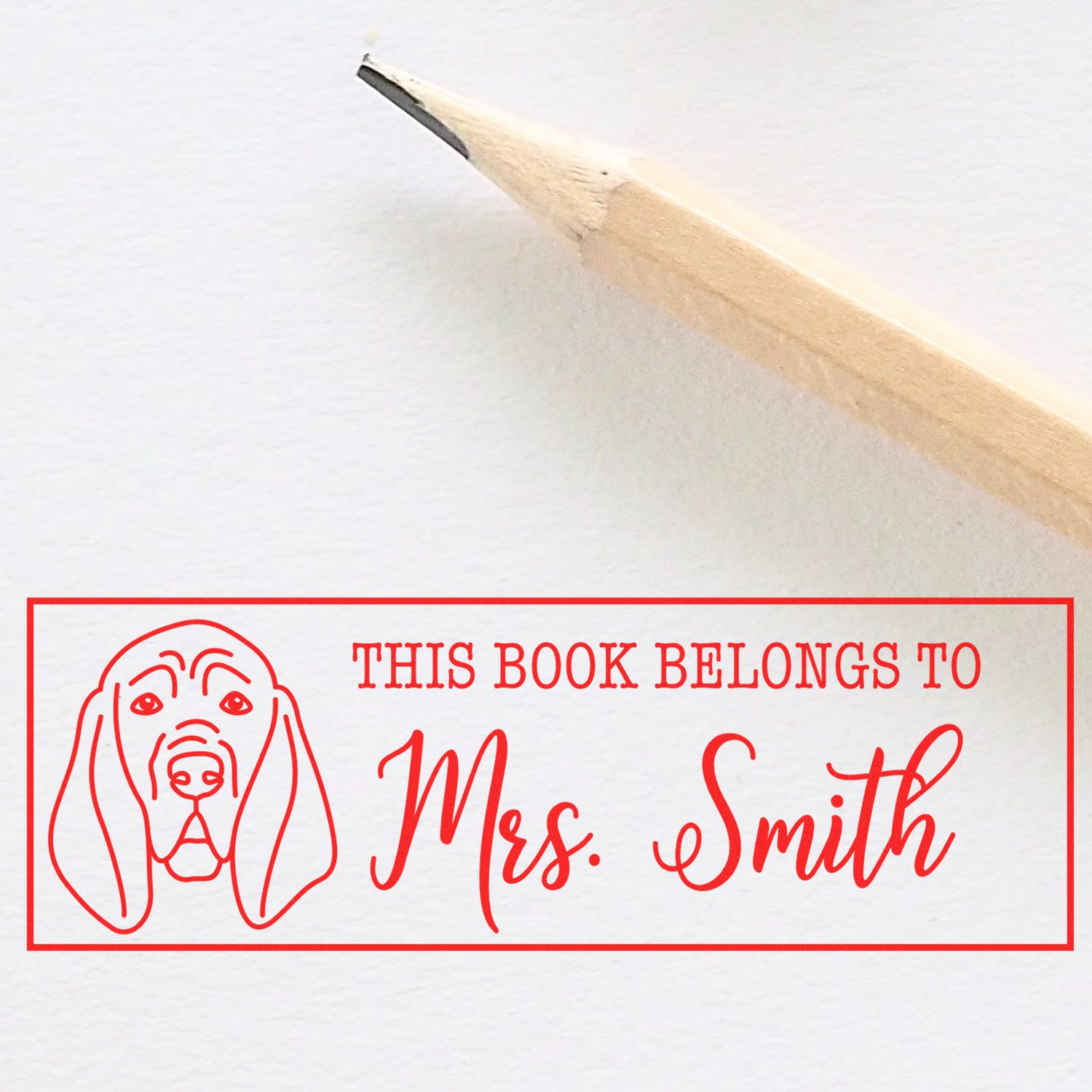 Personalized rubber book stamp with dog illustration reading This Book Belongs to Mrs. Smith for home library marking.