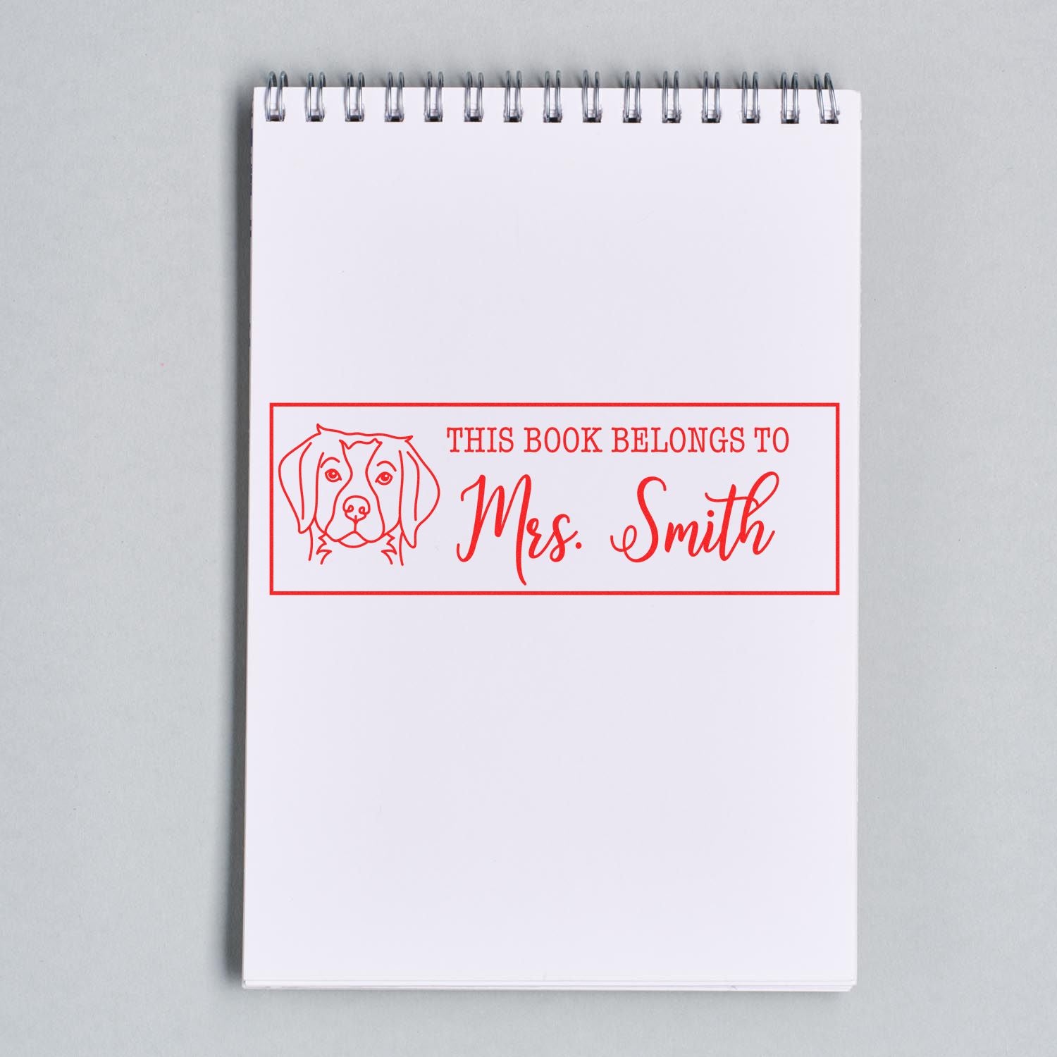 Custom dog rubber book stamp reading This Book Belongs to Mrs. Smith for personalized library labeling.
