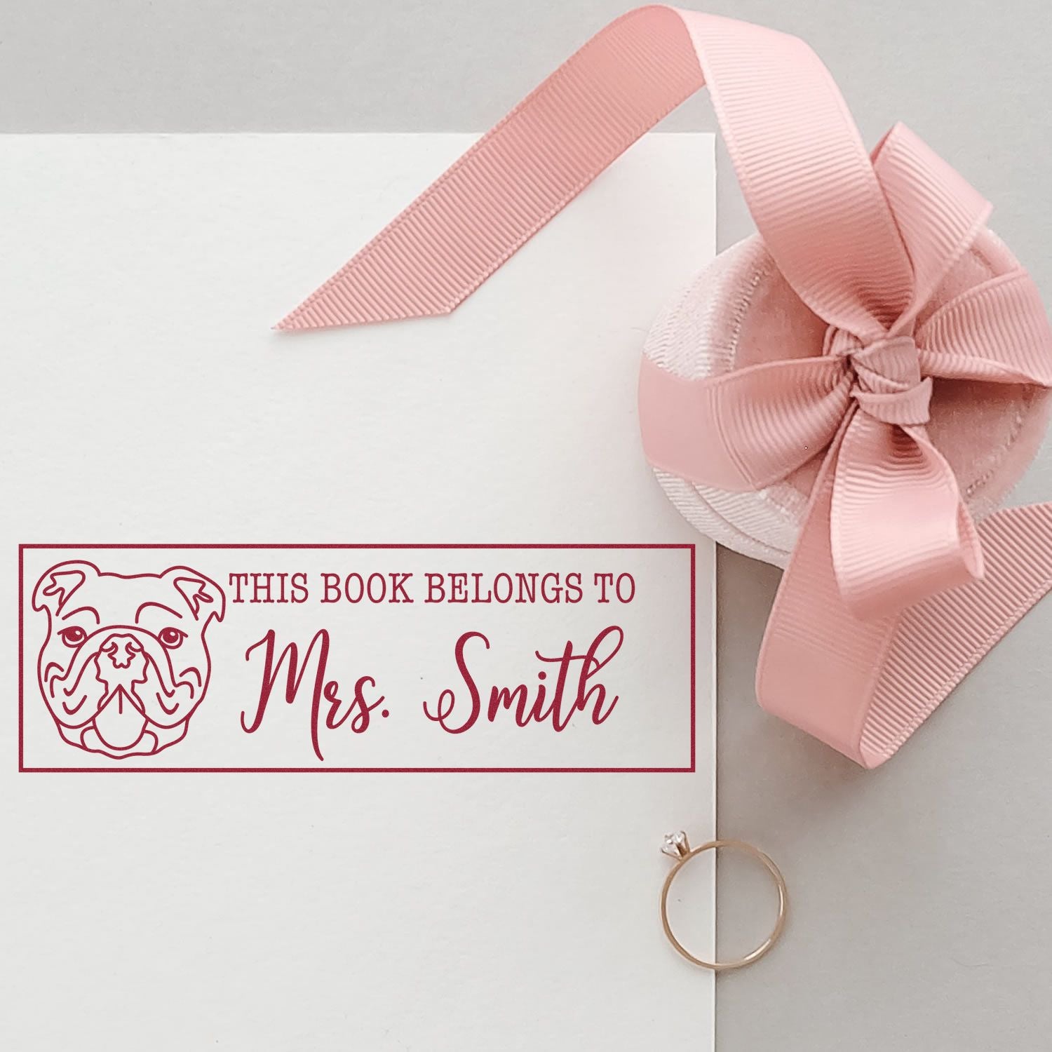 Custom rubber book stamp with bulldog design and This Book Belongs to Mrs. Smith for personalized library marking.