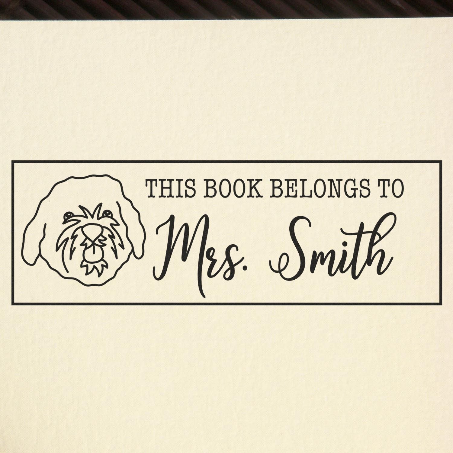 Personalized rubber book stamp with dog illustration and text: This Book Belongs to Mrs. Smith.