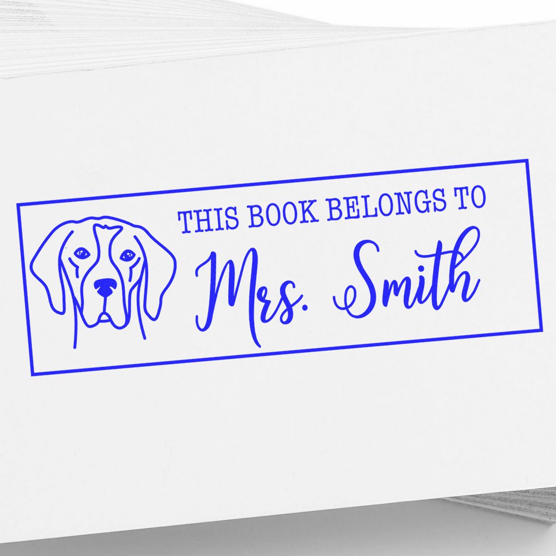 Blue custom rubber stamp with dog icon and This Book Belongs to Mrs. Smith text for personalized bookplate labeling.