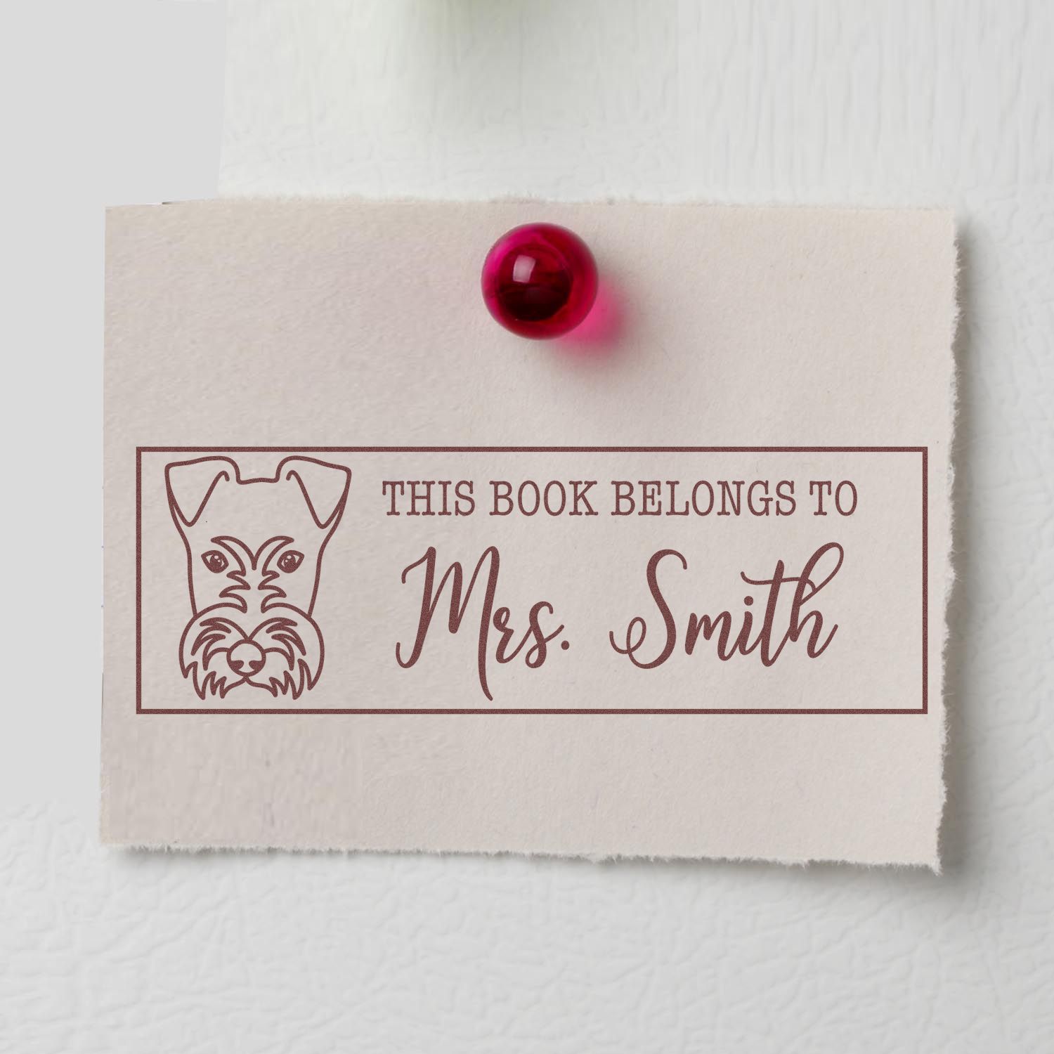 Personalized rubber stamp bookplate with dog illustration reading This Book Belongs to Mrs. Smith for library books.
