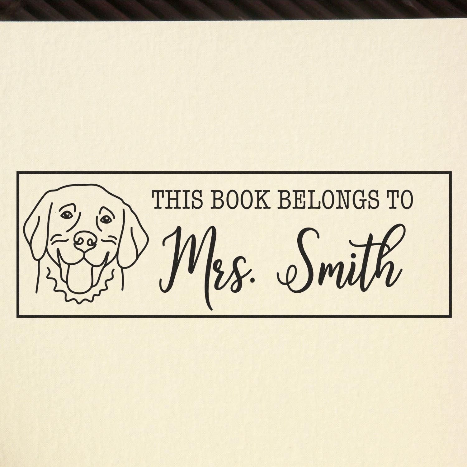 Custom rubber stamp with dog illustration and personalized This Book Belongs to Mrs. Smith bookplate design.
