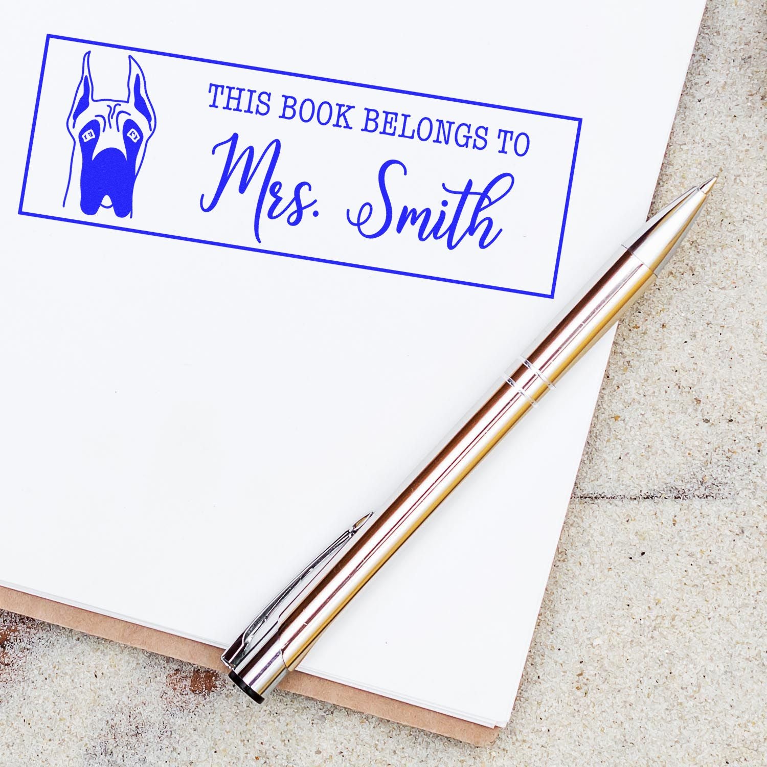Custom rubber stamp for books with dog illustration and This Book Belongs to Mrs. Smith personalized library label.