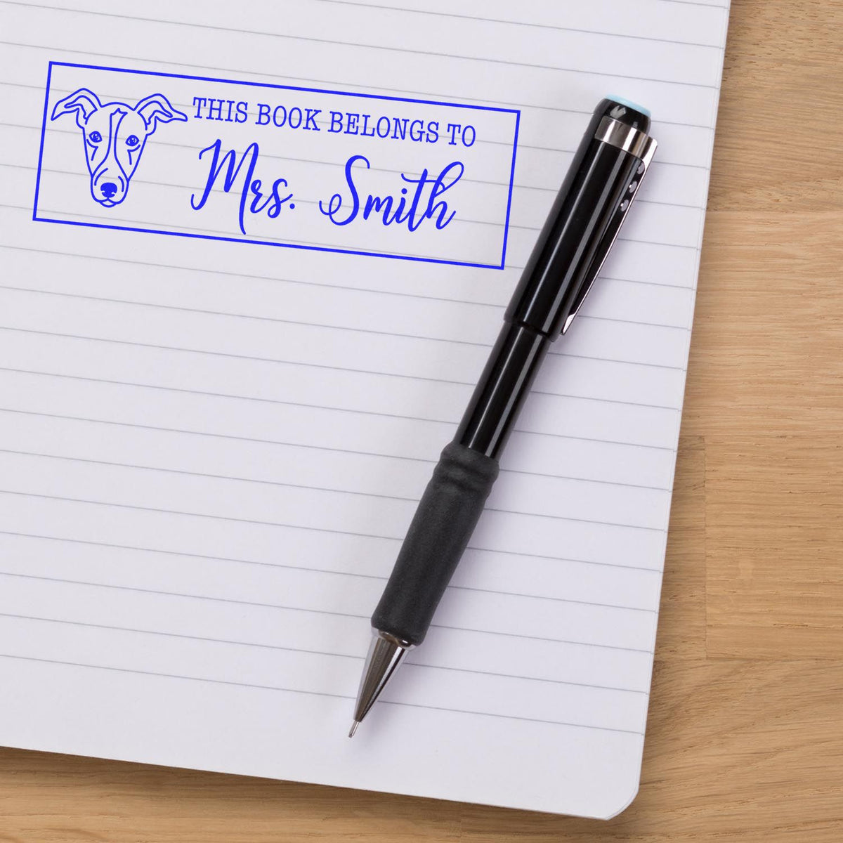 Custom dog book rubber stamp reading This Book Belongs to Mrs. Smith on a notebook, ideal for personalizing books