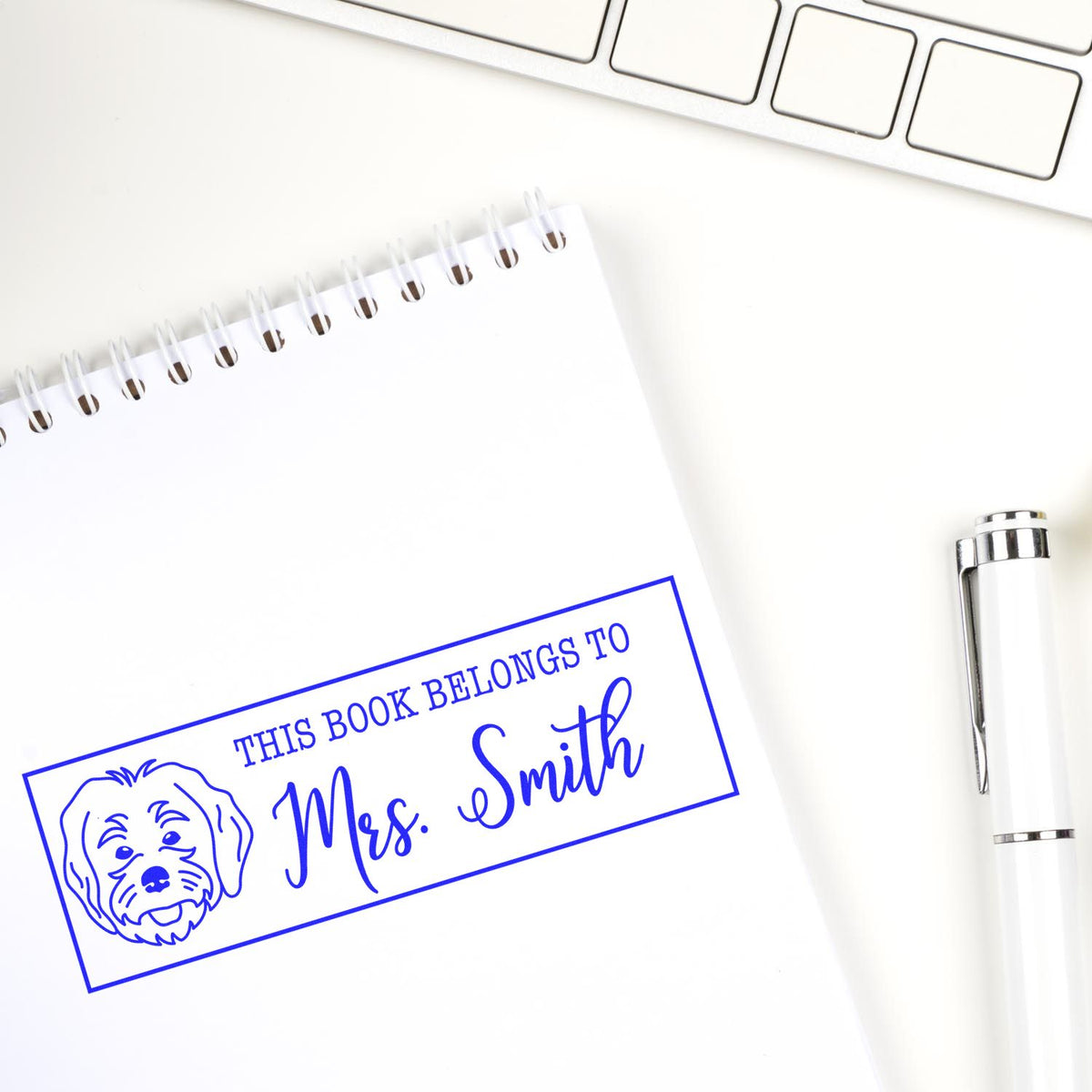 Personalized rubber book stamp for Mrs. Smith with dog design on notebook, plus pen and keyboard on desk.