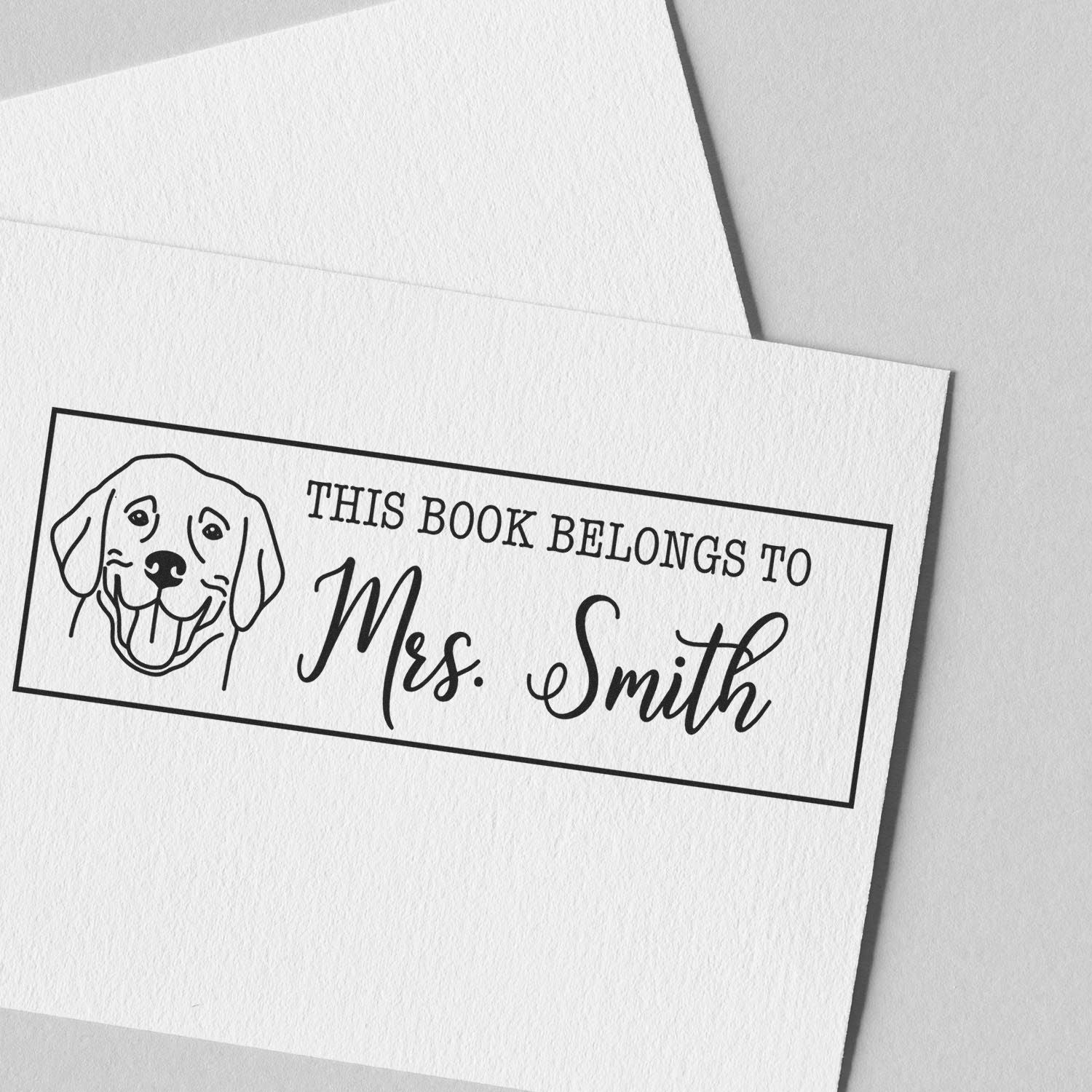 Custom book rubber stamp reading This Book Belongs to Mrs. Smith with dog illustration for personalized library books.
