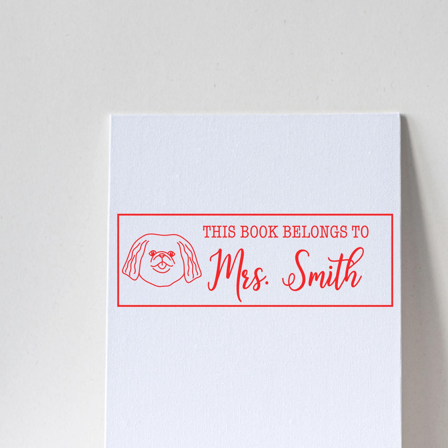 Personalized rubber stamp for books with dog illustration and This Book Belongs to Mrs. Smith text.