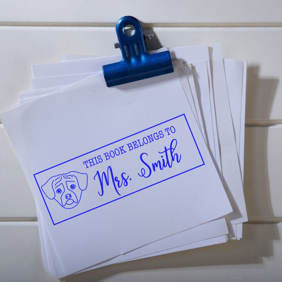 Custom rubber book stamp reading This Book Belongs to Mrs. Smith with dog icon for personalized library labeling.