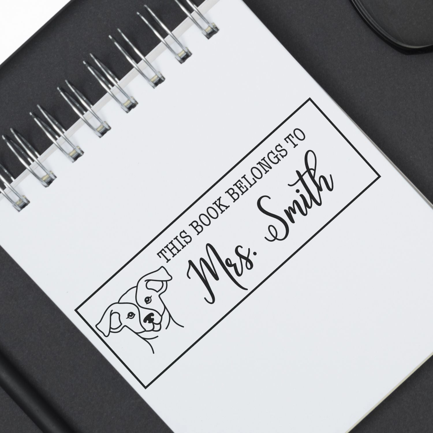 Personalized rubber stamp with dog illustration and This Book Belongs to Mrs. Smith for book ownership.
