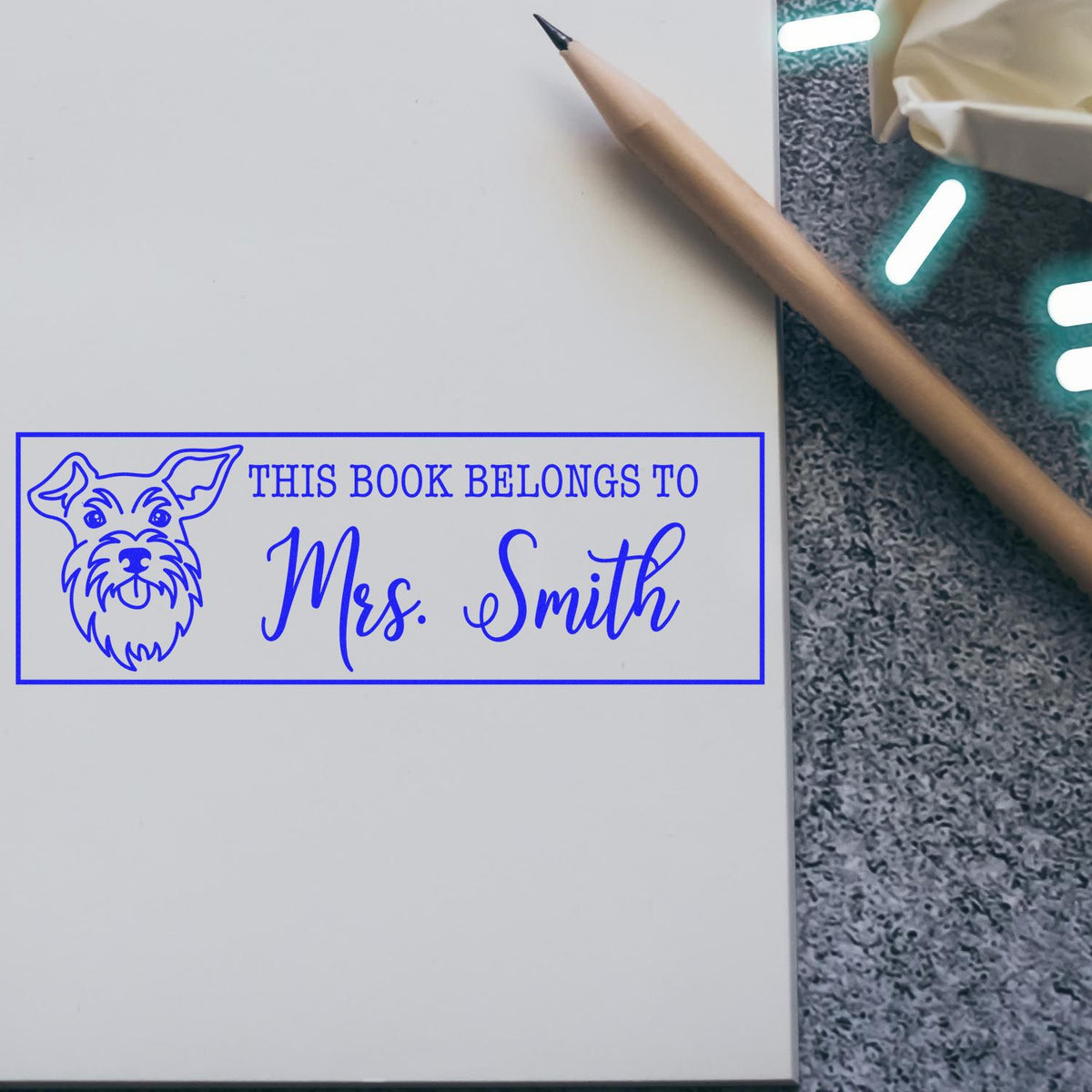 Personalized rubber book stamp with dog design and This Book Belongs to Mrs. Smith for marking owned books.