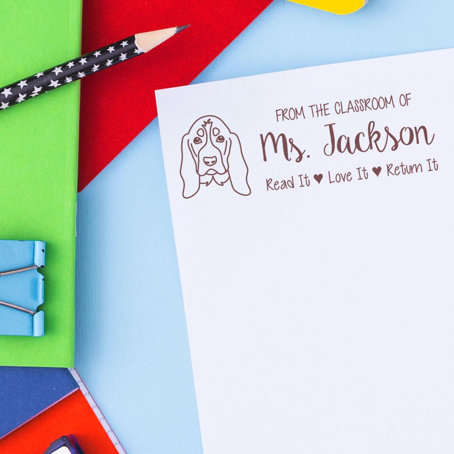 Custom teacher rubber stamp with dog design and name, marking books, papers, and classroom supplies from Ms. Jackson.