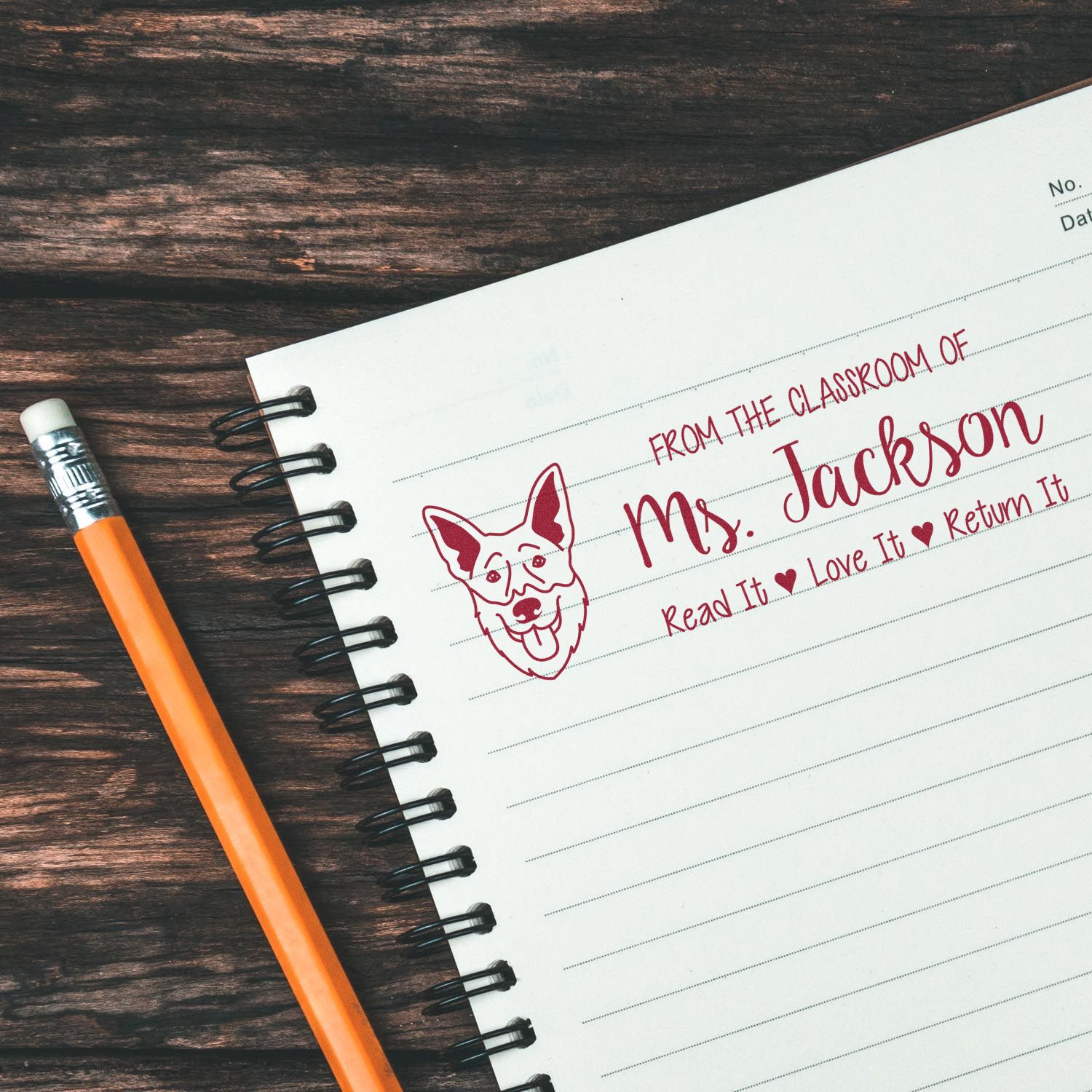 Personalized teacher rubber stamp with dog design, used for classroom books and assignments on a notebook page.