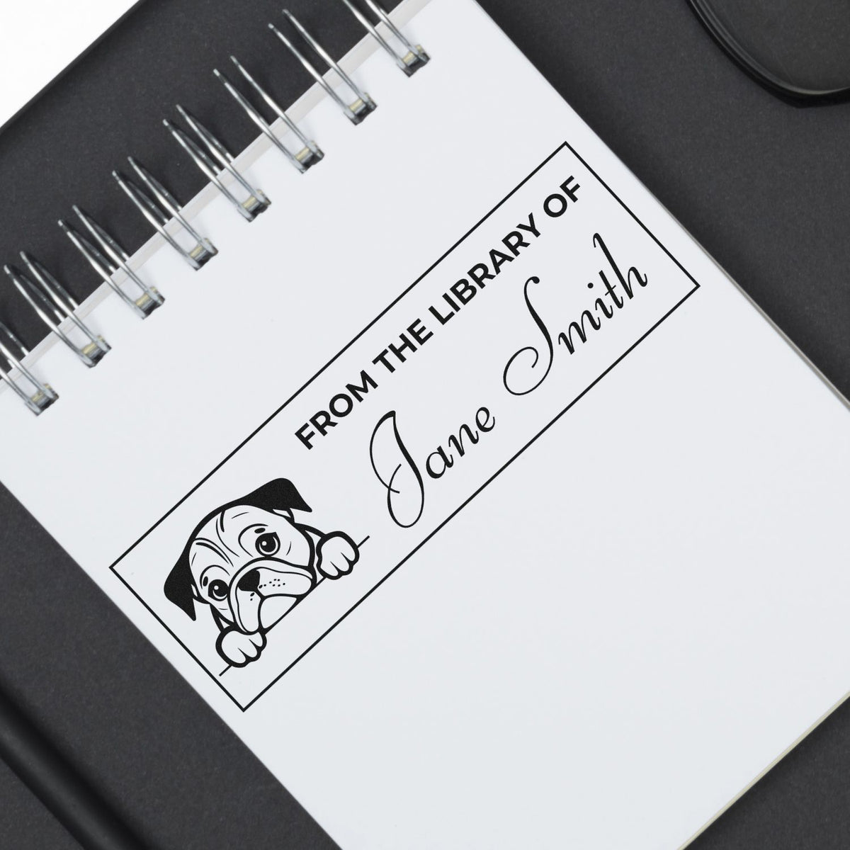 Custom rubber stamp mockup reading From the Library of Jane Smith with dog illustration for personalized library book labels.