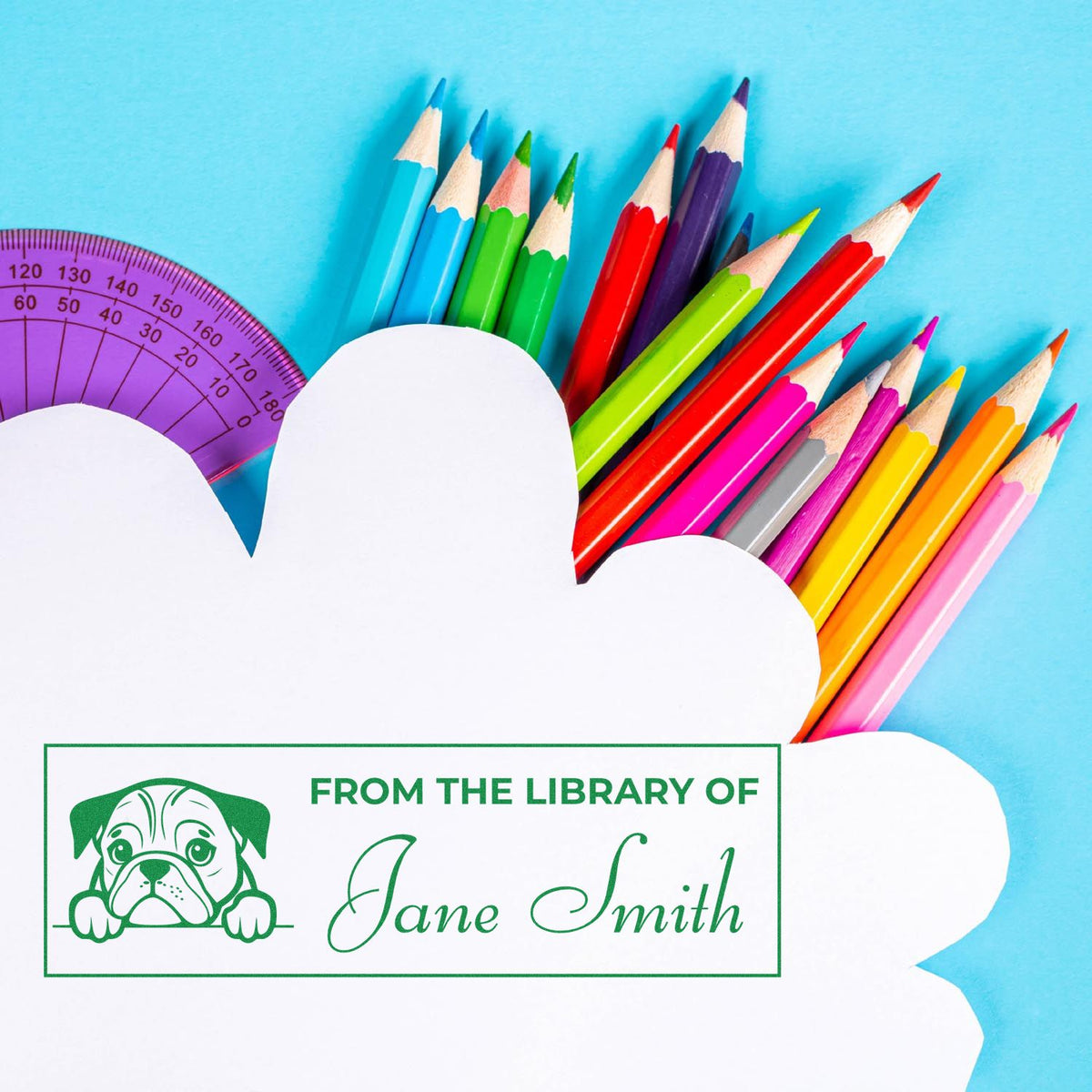 Personalized library rubber stamp with dog icon and Jane Smith name, displayed with colorful pencils and ruler.
