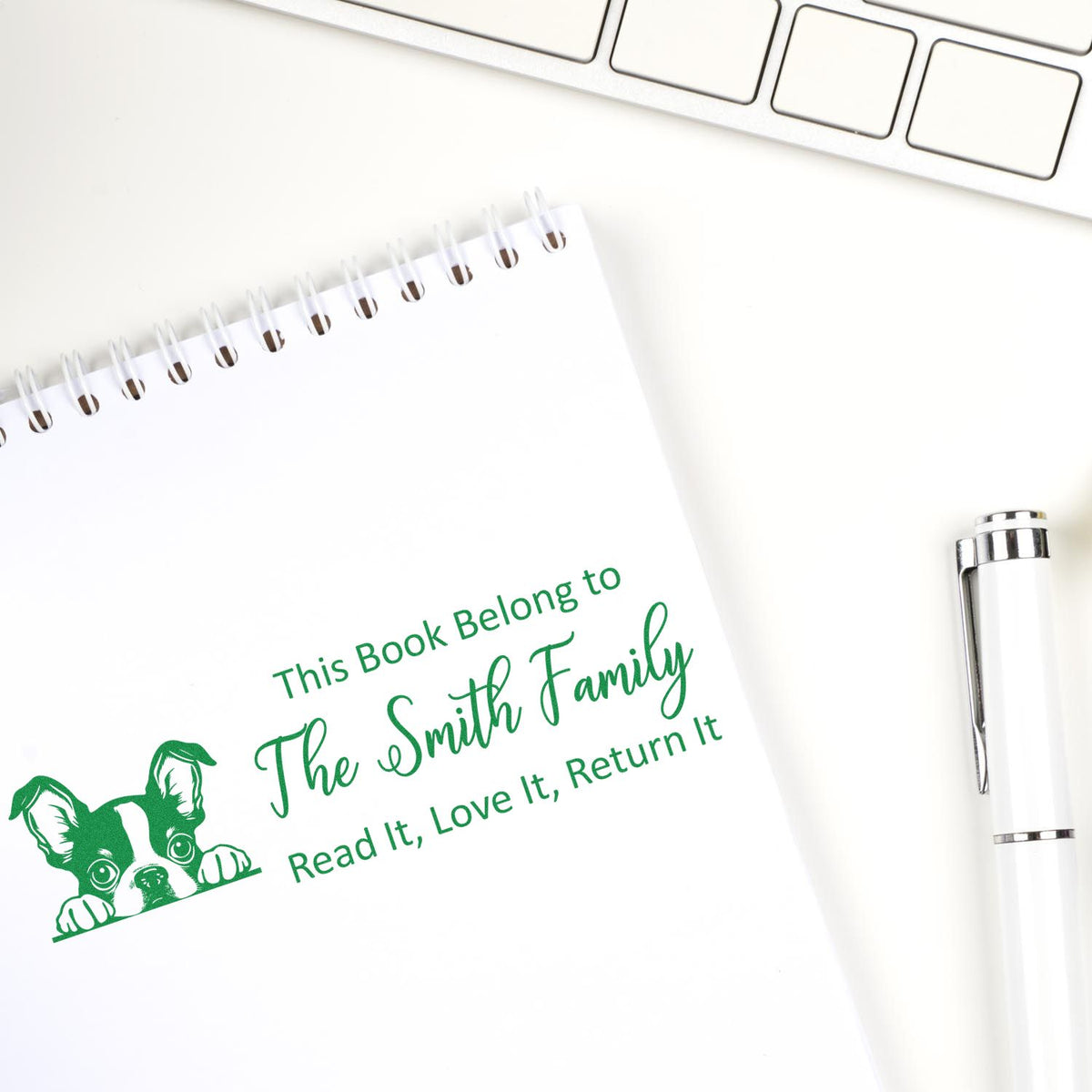 Personalized rubber book stamp with dog design for The Smith Family, marking notebook pages with a custom book belongs to stamp.