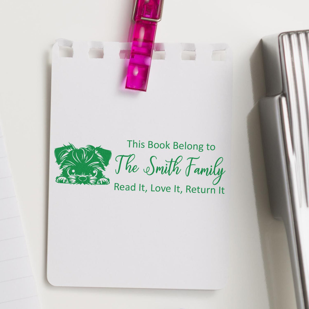 Custom bookplate rubber stamp on notebook reading This Book Belongs to The Smith Family with dog design.