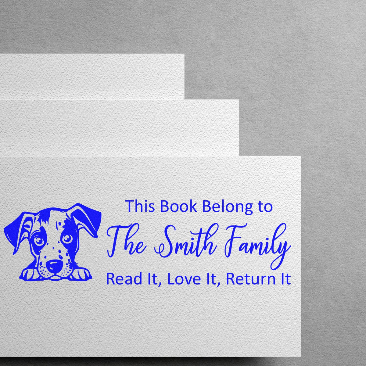 Personalized rubber book stamp with dog illustration and This Book Belongs to The Smith Family, Read It, Love It, Return It message.