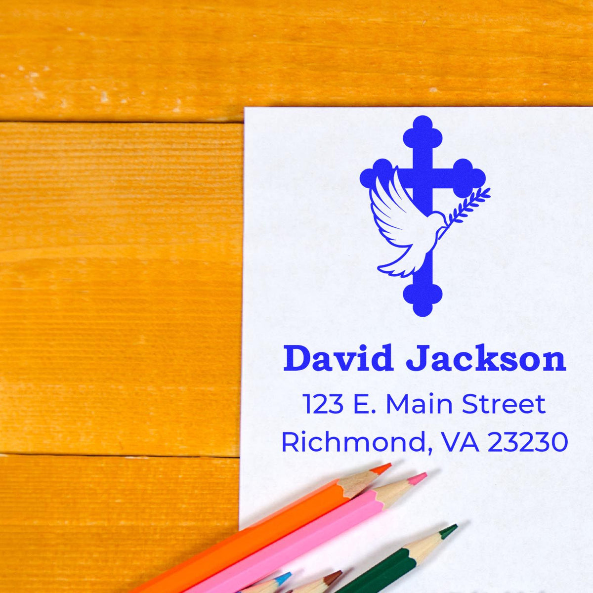 Custom rubber stamp design with dove and cross logo for David Jackson address labels and stationery on a wooden desk.