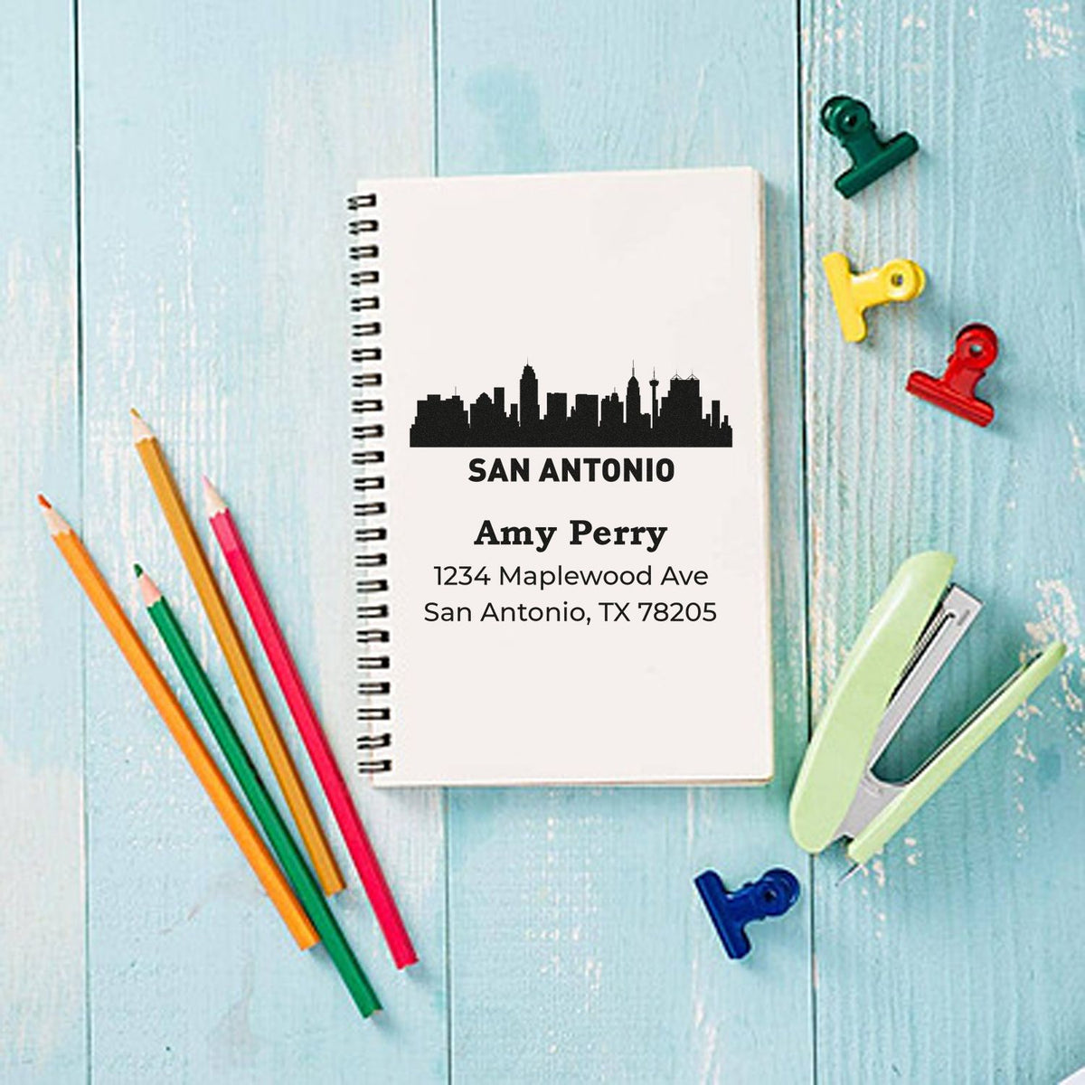 Custom San Antonio return address rubber stamp for Amy Perry, featuring skyline design and address on a notebook.