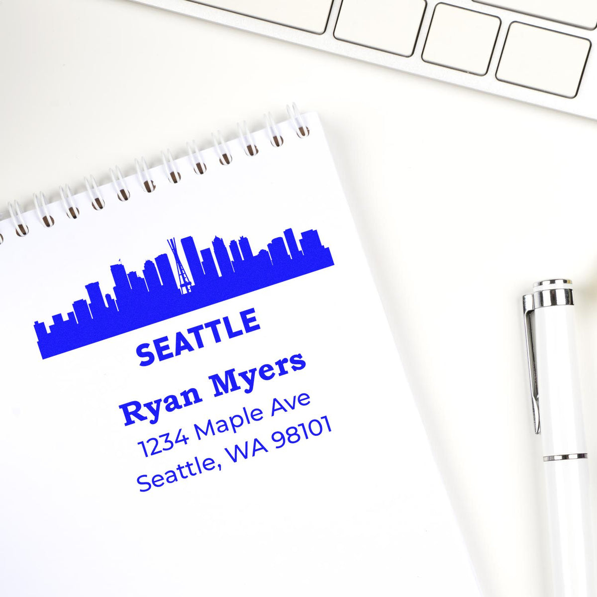 Custom address rubber stamp with Seattle skyline design, name, and address on notebook for personalized business stationery.