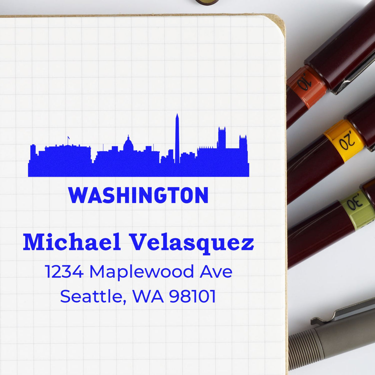 Custom Washington skyline address rubber stamp with name and Seattle, WA address on notebook paper.