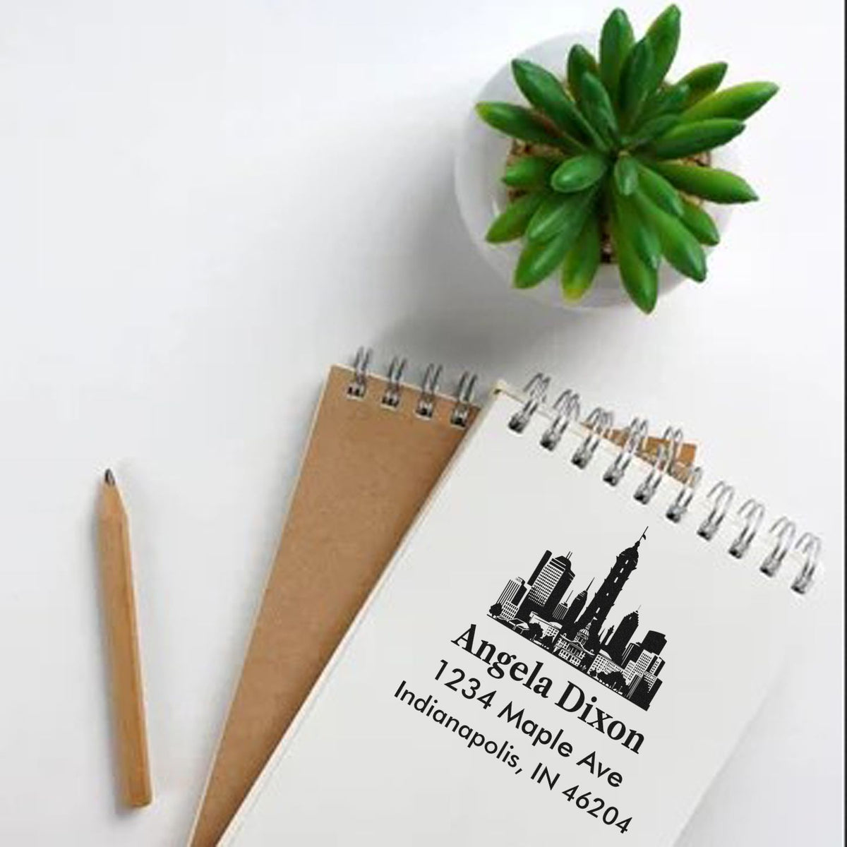 Custom address rubber stamp with city skyline logo on a spiral notebook, featuring name and Indianapolis return address