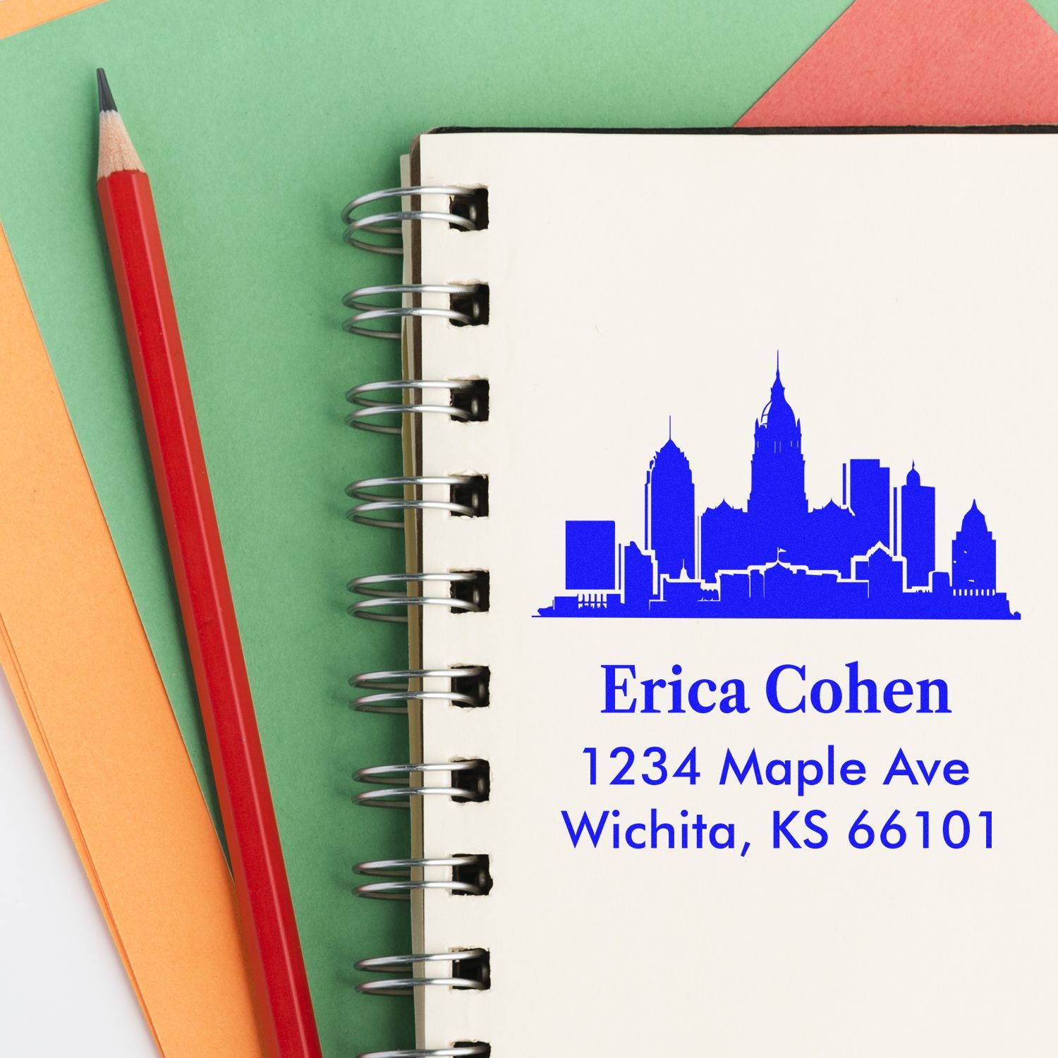 Personalized return address rubber stamp with skyline design, name, and Wichita, KS address on notebook mockup.