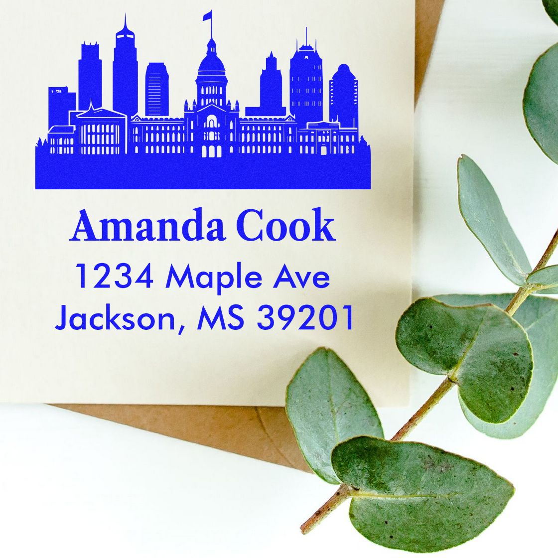 Personalized return address rubber stamp with skyline design, showing Amanda Cook, 1234 Maple Ave, Jackson, MS 39201.