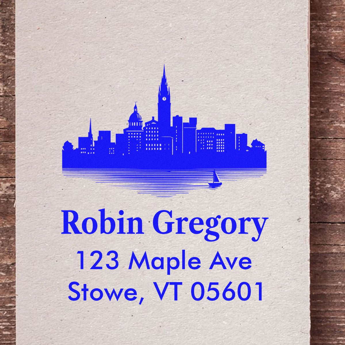 Personalized rubber return address stamp with skyline design for Robin Gregory, 123 Maple Ave, Stowe, VT 05601.