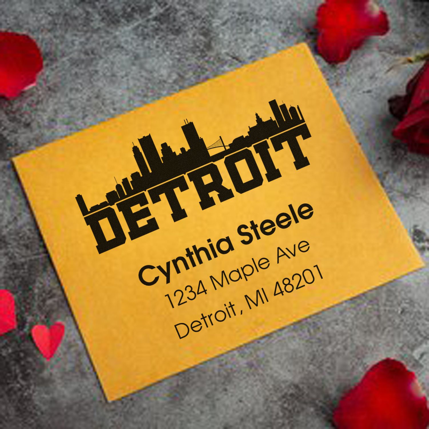 Personalized Detroit address rubber stamp with skyline design and Cynthia Steele return address on a yellow envelope.