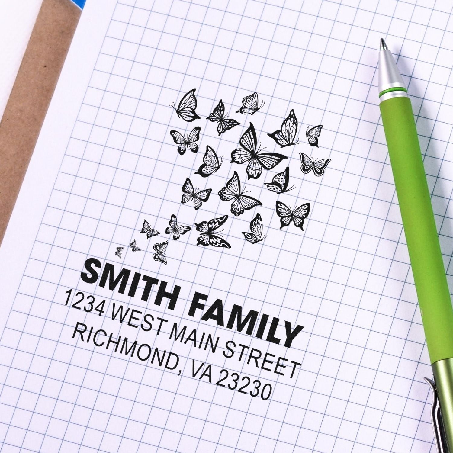 Custom butterfly address rubber stamp sample with Smith Family name and Richmond, VA 23230 on graph paper.