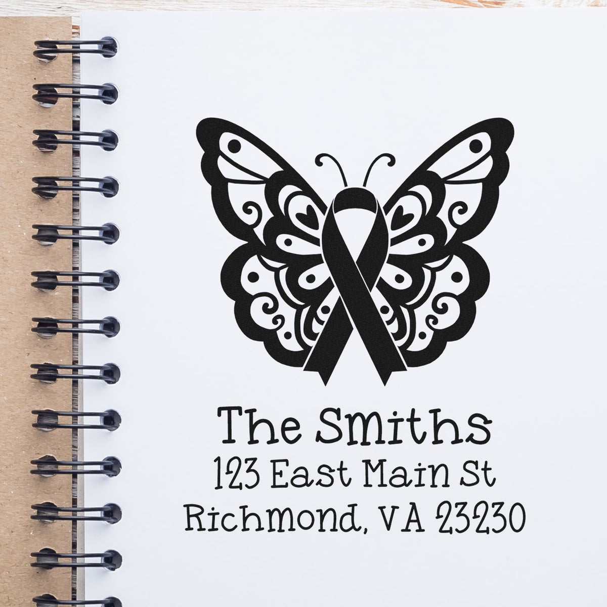 Custom rubber stamp with butterfly awareness ribbon, family name, and address for personalized stationery.