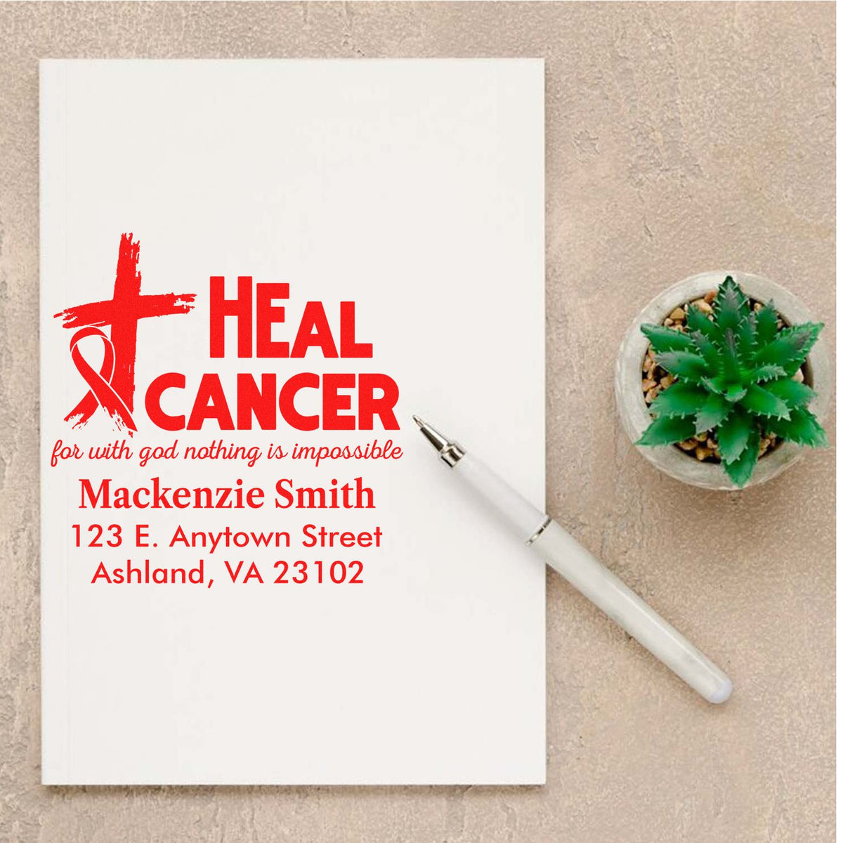 Personalized Heal Cancer rubber stamp with faith ribbon, name and address, shown on a note card with pen and succulent.