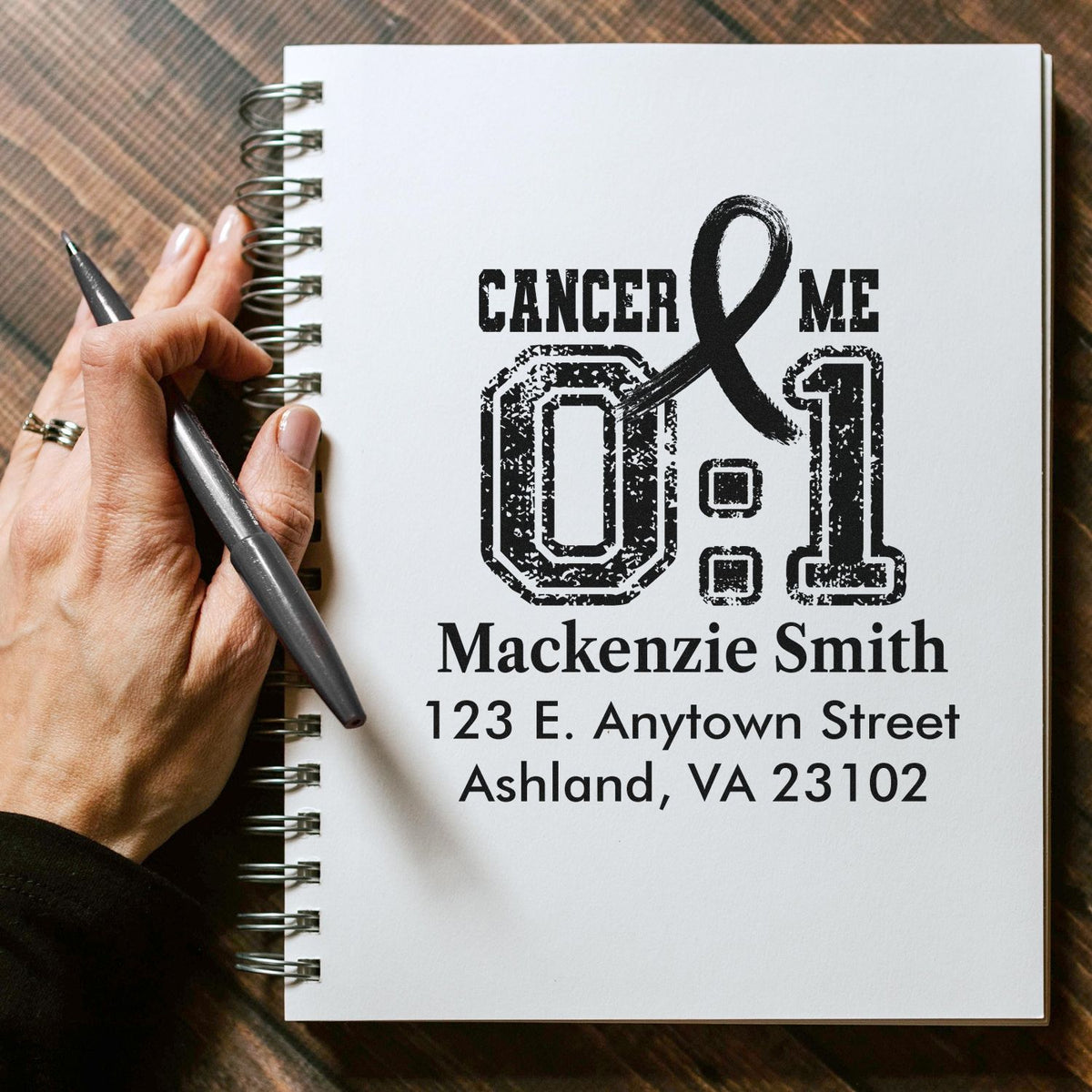 Custom address rubber stamp mockup with Cancer Me 0:1 design and personalized name for cancer awareness stationery.