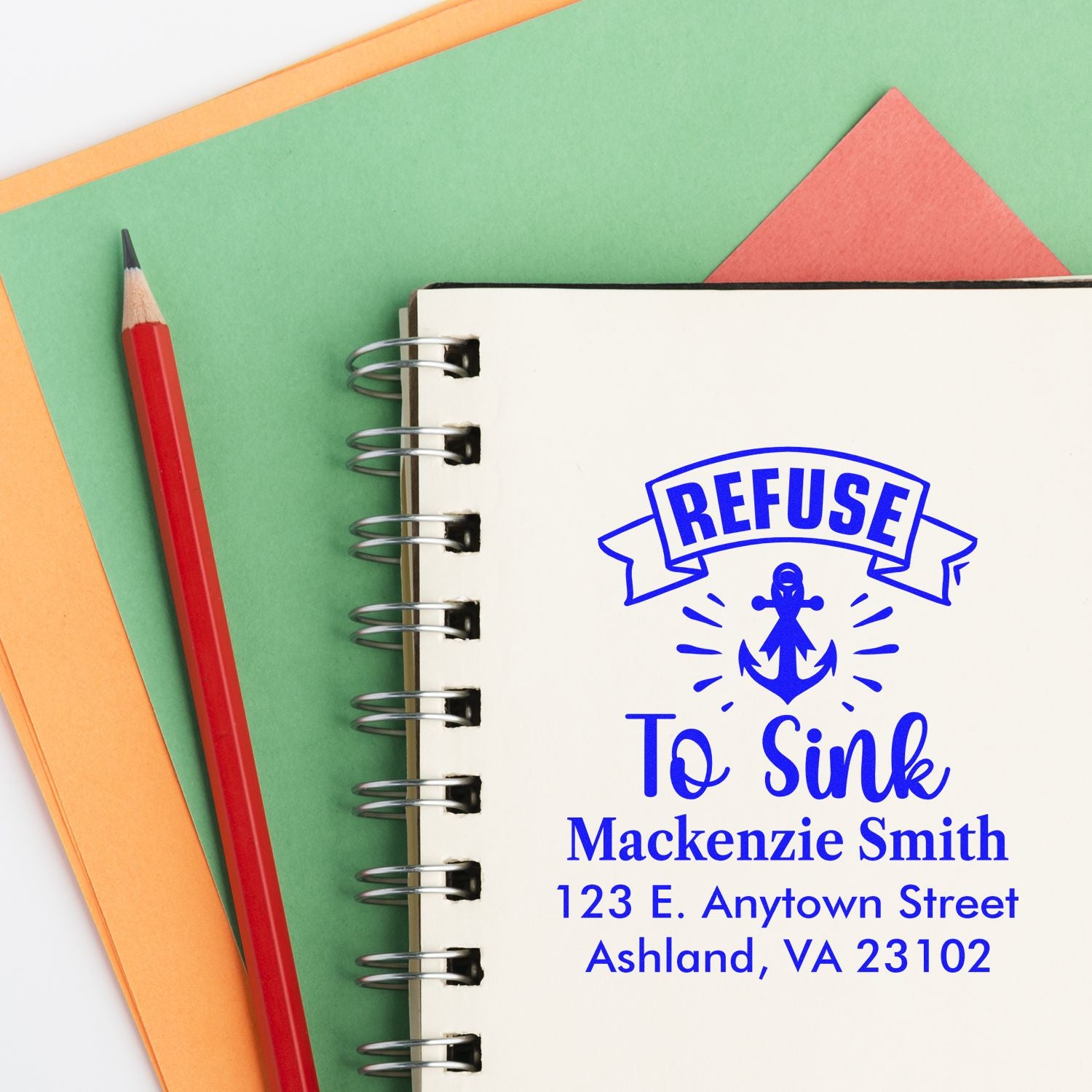 Custom rubber stamp with Refuse to Sink anchor design and personalized name and address on a notebook.