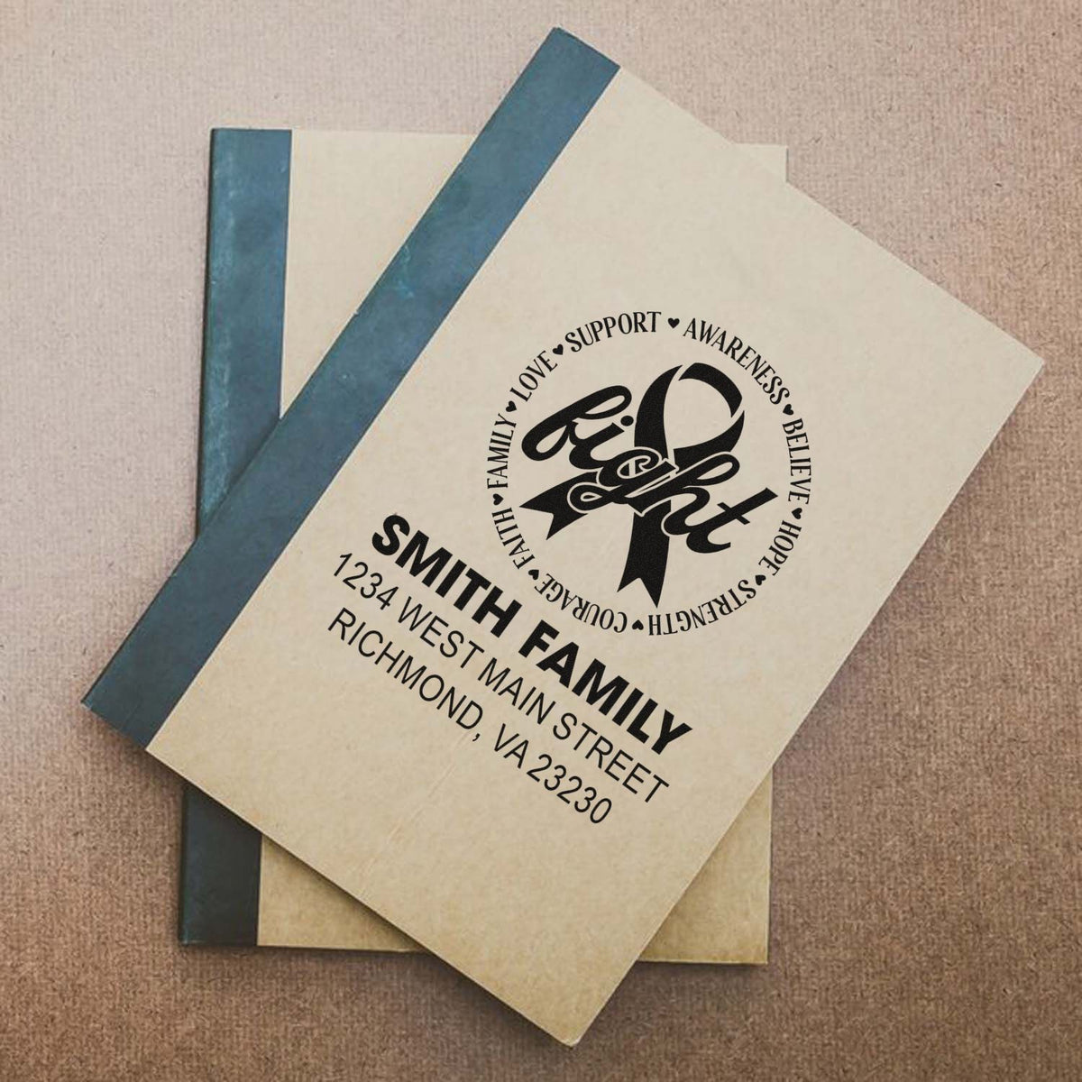 Personalized family address rubber stamp with awareness ribbon design on notebook cover.