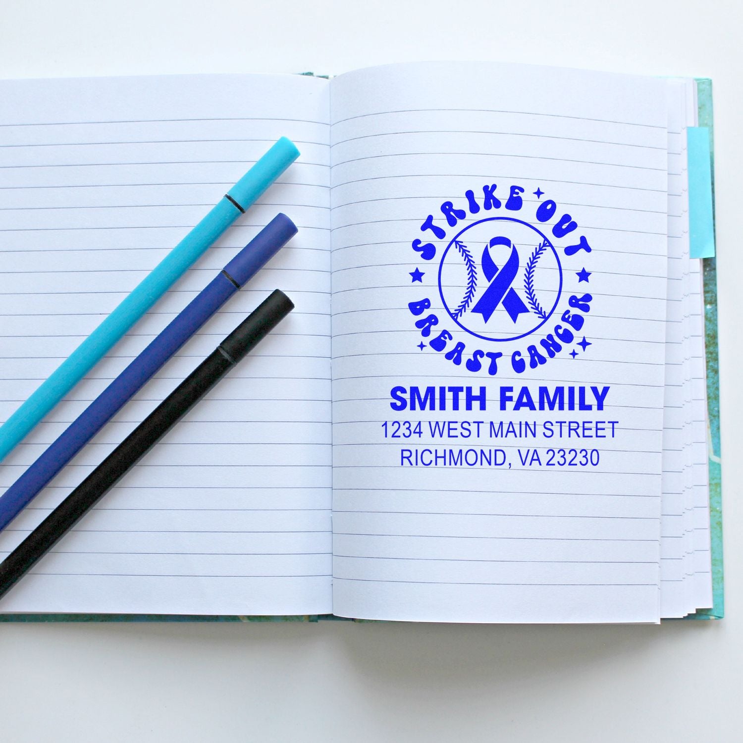 Custom breast cancer awareness return address rubber stamp with ribbon logo and Smith Family address on notebook page.