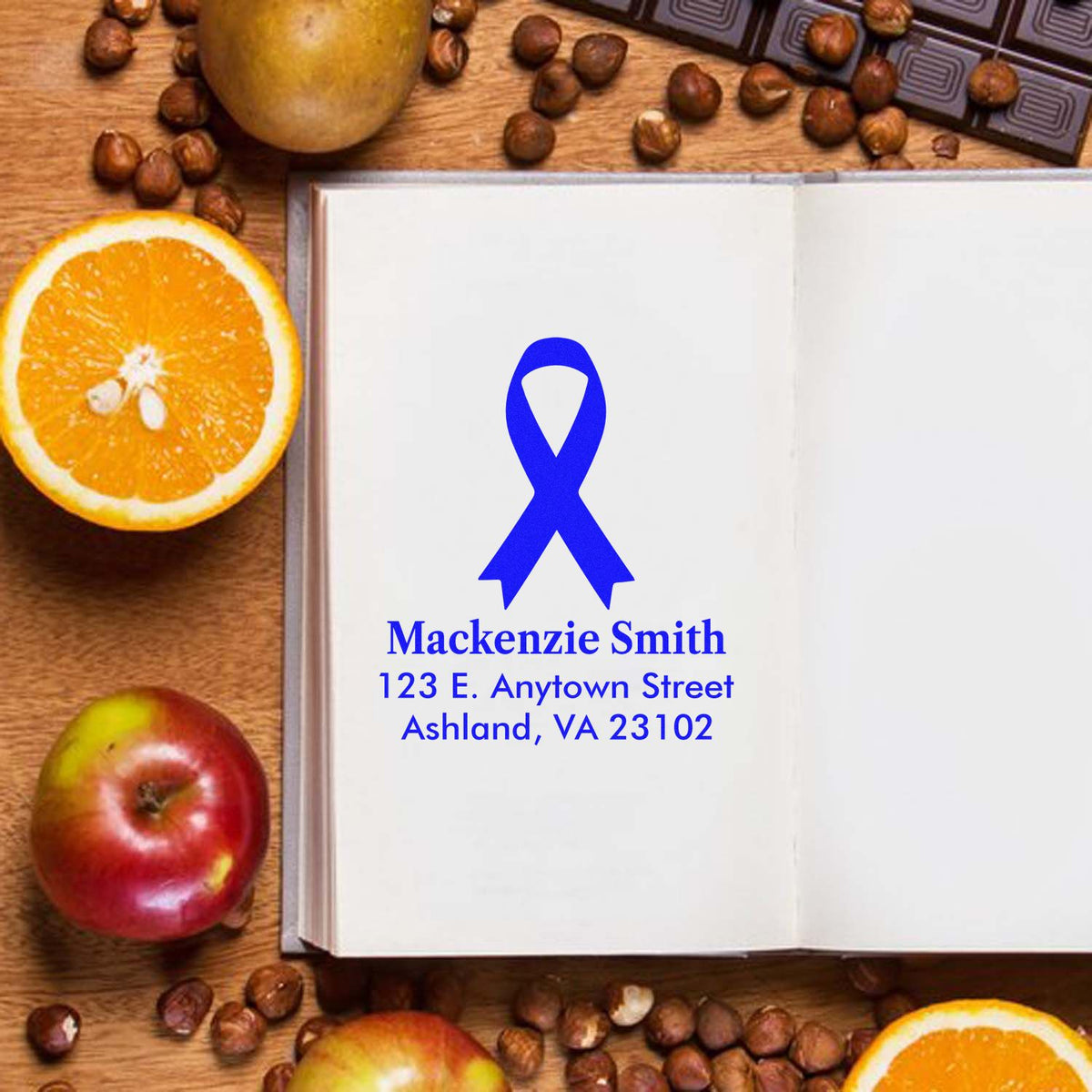 Personalized blue ribbon address rubber stamp imprint on an open notebook with name and mailing address.