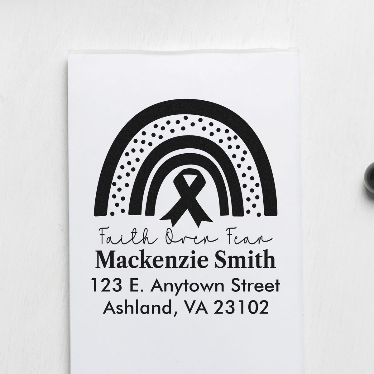 Custom rubber address stamp with rainbow and ribbon design for personalized mailing envelopes.