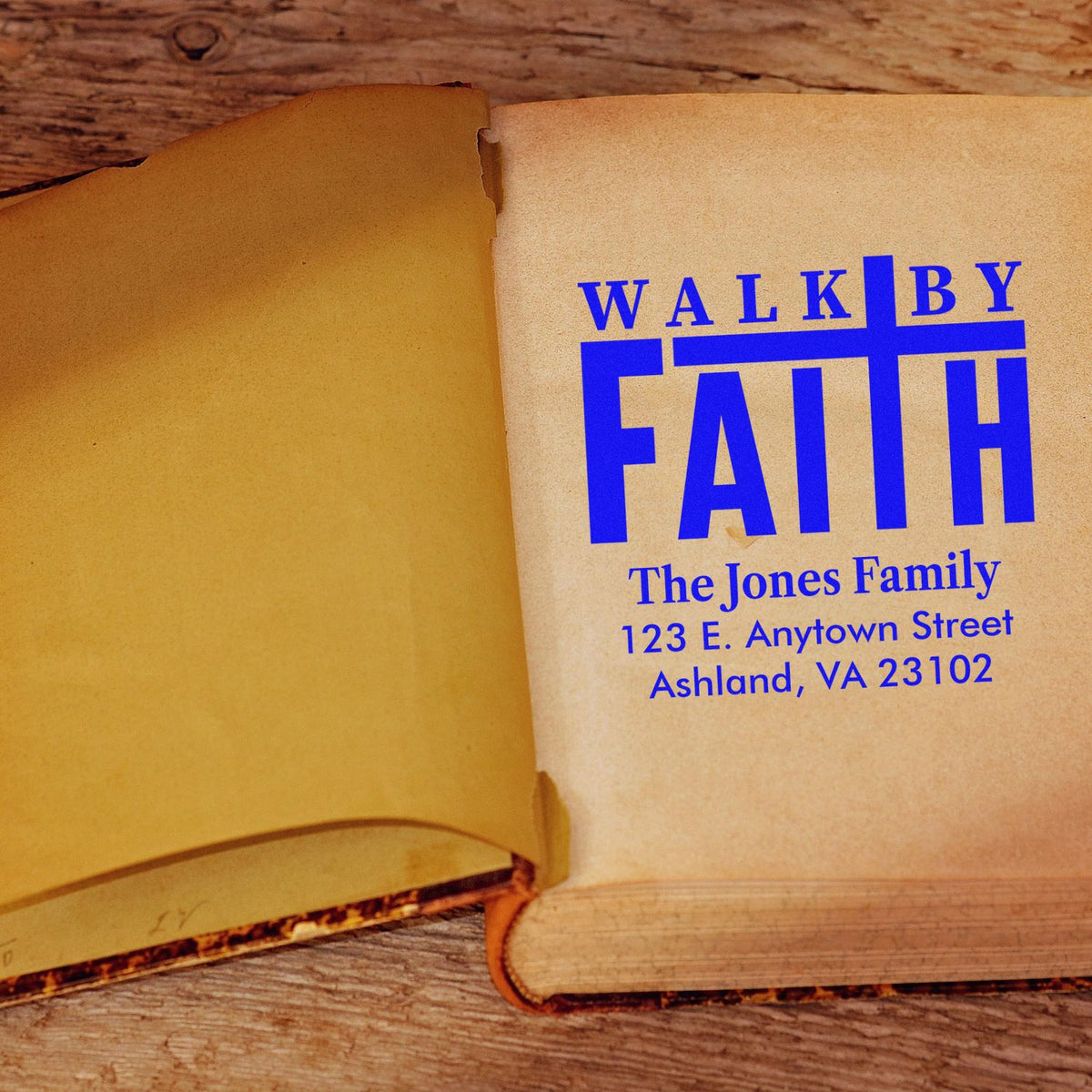 Personalized religious return address rubber stamp reading Walk by Faith for The Jones Family, with name and address on a book page.