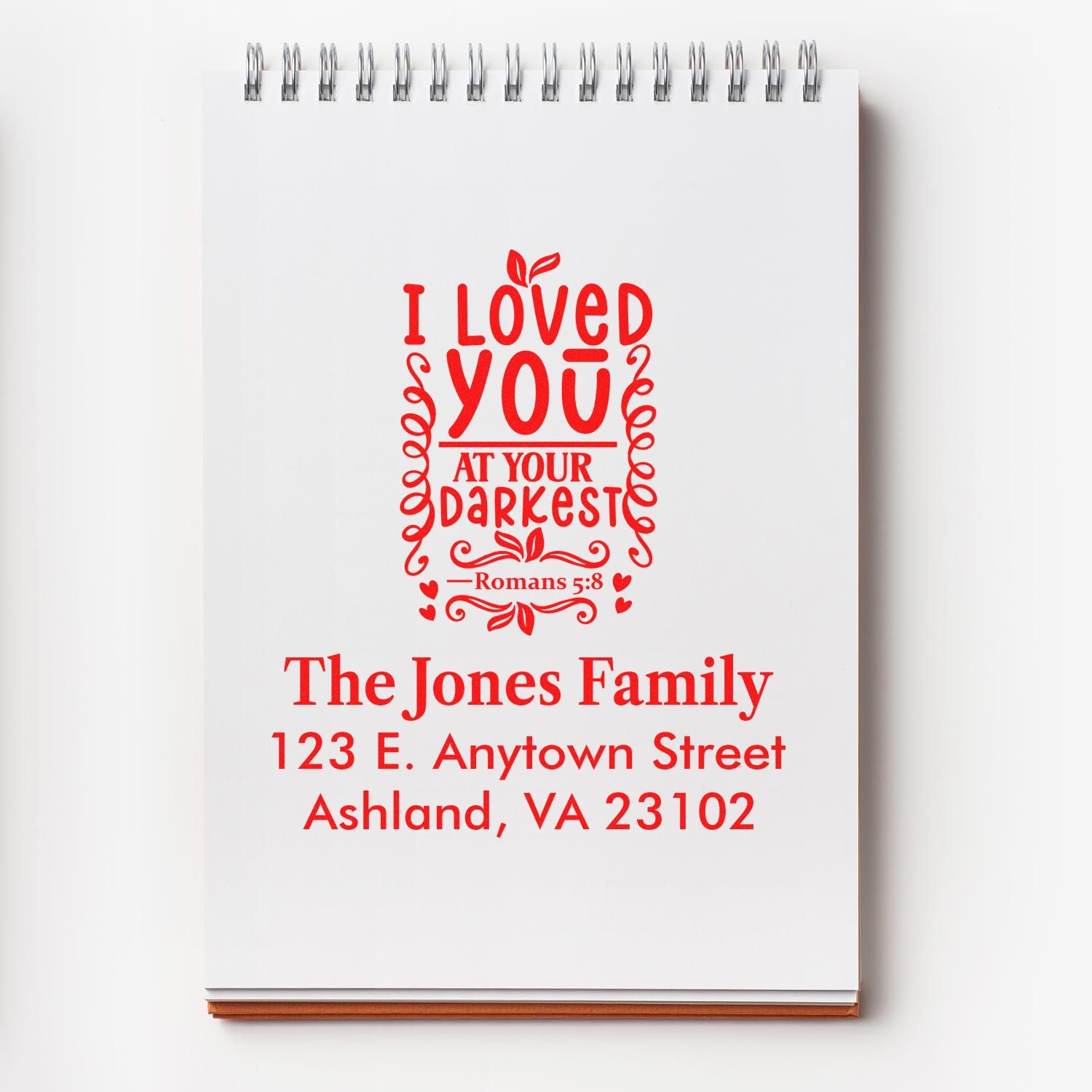 Personalized Christian rubber stamp proof with Romans 5:8 verse, family name, and address for custom return mail.